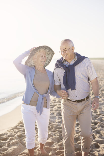 日出老年夫妇在沙滩 退休和暑假的概念团聚照明人际关系