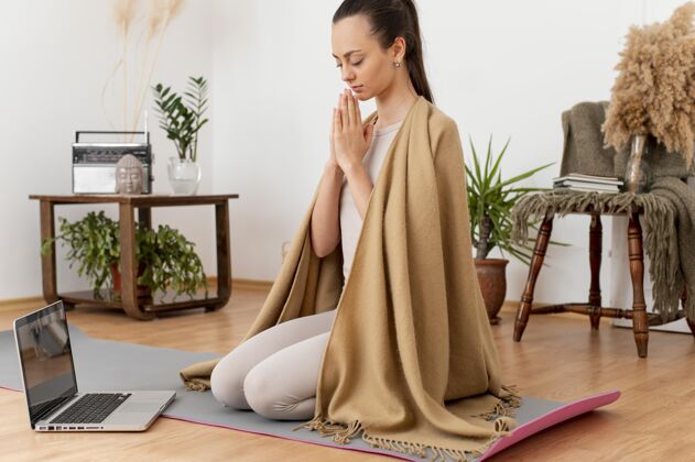 耳机在家坐在垫子上冥想的女人瑜伽技术冥想
