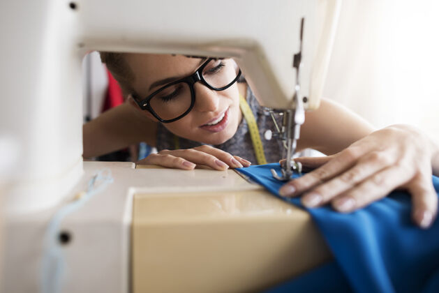 车间年轻裁缝在缝纫机上工作裁缝女性退休