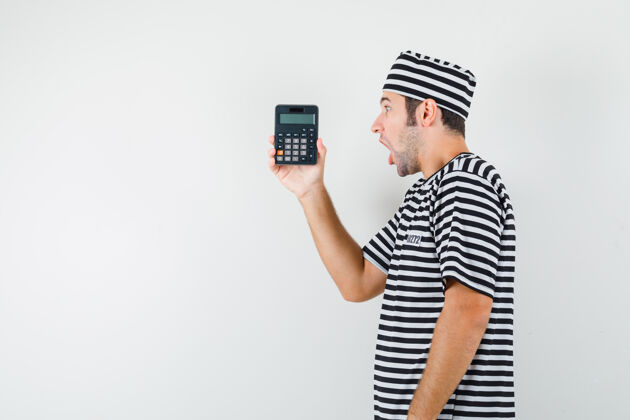 热一个穿着t恤 戴着帽子的年轻男人看着计算器 神情好奇季节年轻姿势