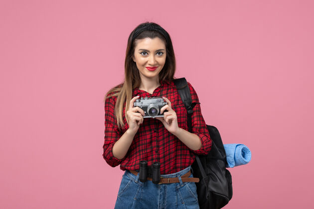 年轻女性正面图：穿着红色衬衫的年轻女性 在粉色桌子上放着相机 模特拍照相机头发黑发