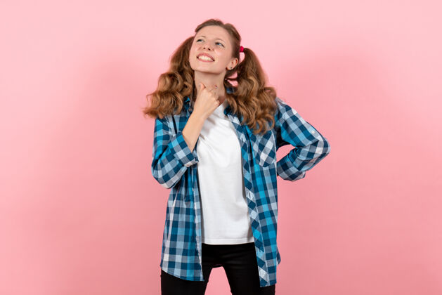 情绪正面图身着蓝色格子衬衫的年轻女性在浅粉色背景上摆姿势女孩青春情感模特时尚小子肖像成人女孩