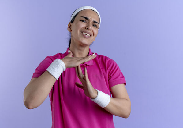 紫色年轻恼怒的白人运动女子戴着头带和腕带手势超时手上的紫色标志与复制空间年轻佩戴手