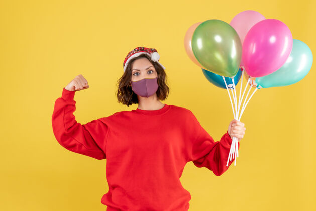 年轻女人正面图年轻女子拿着气球 戴着黄色的无菌面具派对正面情感