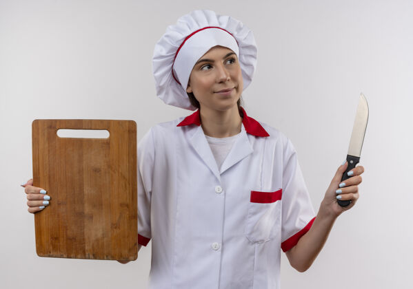 板身着厨师制服的年轻快乐的白人厨师女孩手持刀和白板 留有复印空间刀制服女孩