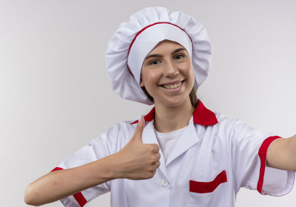 空间身着厨师制服的年轻高加索厨师女孩微笑着 假装拿着相机 竖起大拇指对着白色 留着复印空间拇指复制向上