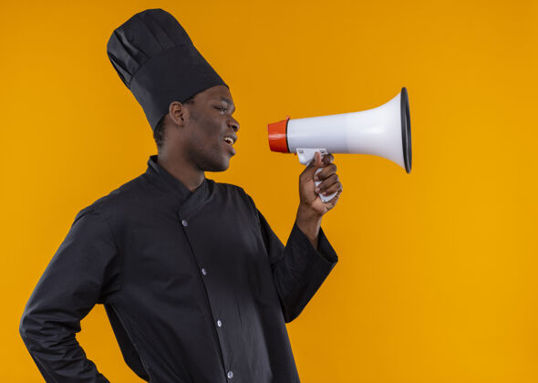 非裔美国人年轻恼怒的非洲裔美国厨师身着厨师制服 站在一旁 通过橙色的扩音器讲话 并留有复印空间空间恼怒扬声器