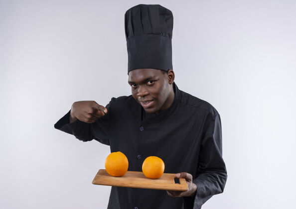 非裔美国人年轻快乐的非洲裔美国厨师身着厨师制服 拿着橘子放在白色的砧板上 留有复印空间董事会空间厨师