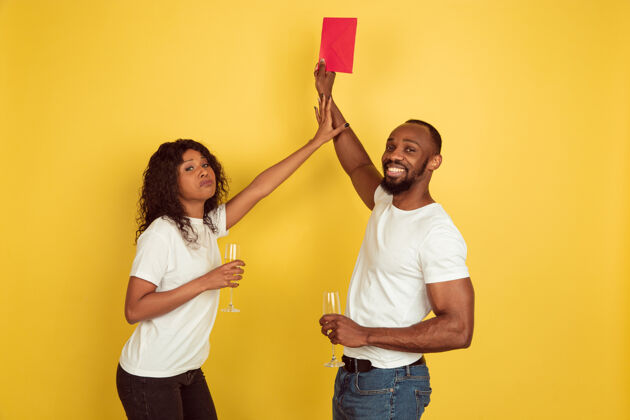 情人节送红包快乐的非洲裔美国夫妇隔离在黄色的墙壁上人类情感的概念 面部表情 爱情 关系 浪漫的节日民族浪漫肖像