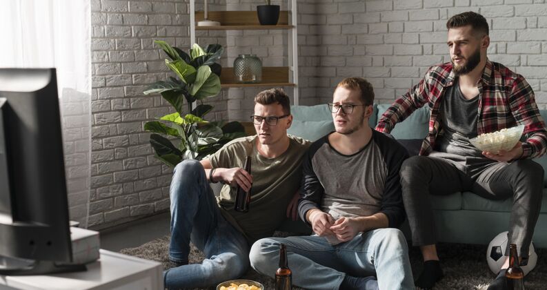 伙伴男性朋友在电视上观看啤酒和足球运动的正面图一起看电视电视