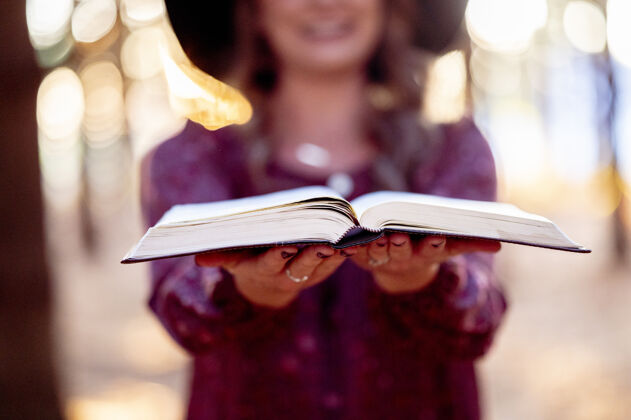 学习一个女人拿着一本打开的书的选择性聚焦镜头历史文学概念