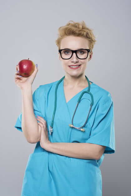 医护人员拿着苹果的女牙医肖像持有外科医生