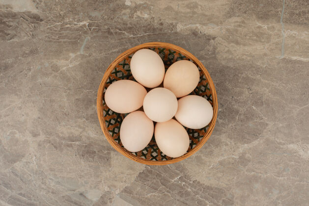 少大理石桌上放着一篮子白鸡蛋生的胆固醇贝壳
