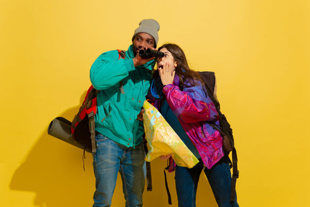爱一对快乐的年轻旅游夫妇的画像 他们的包被隔离在黄色的工作室墙上旅行欢呼朋友