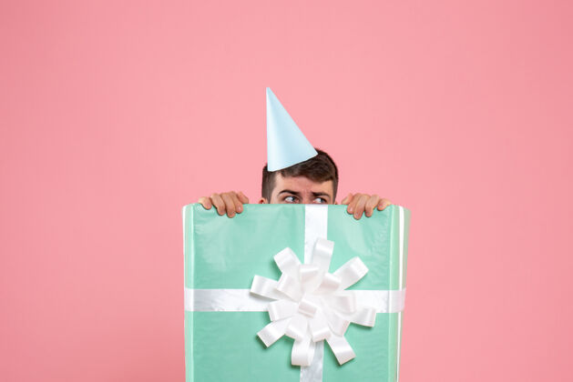 立场正面图年轻男性站在礼物盒内浅粉色圣诞照片情感人年轻男性庆祝里面