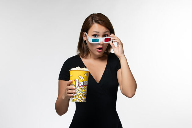 前面前视图年轻女性手持爆米花包在一个白色表面上的d太阳镜爆米花电影院电影