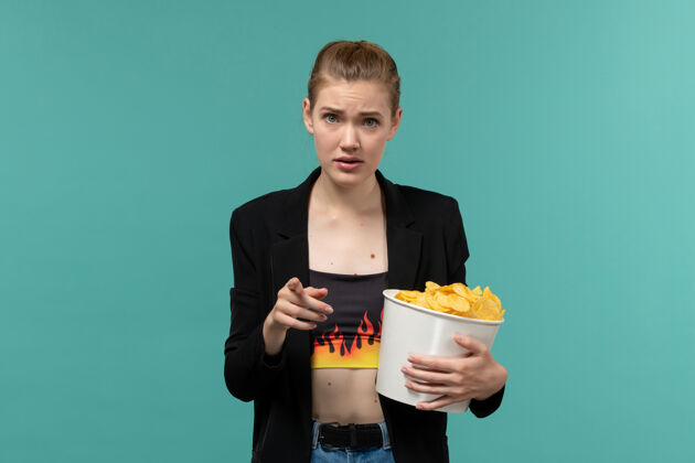 电影前视图年轻女性在电影院吃薯片看电影在蓝色的表面服务员电影土豆