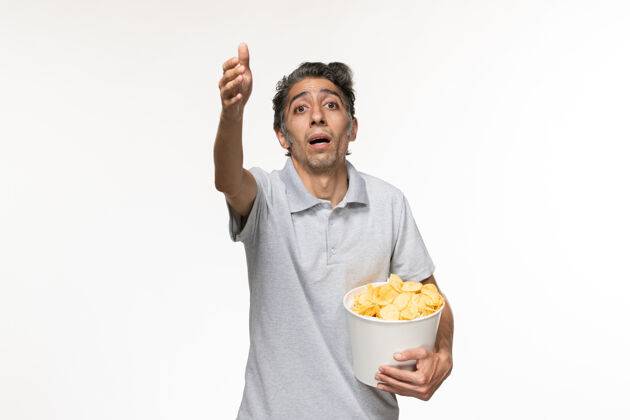 电影正面图：年轻的男性拿着薯片在白色的表面上孤独食物电影