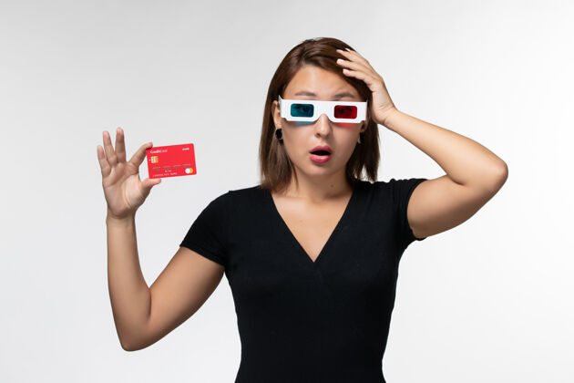 思考正面图年轻女性戴着d墨镜拿着银行卡 在白色的表面思考电影前面电影