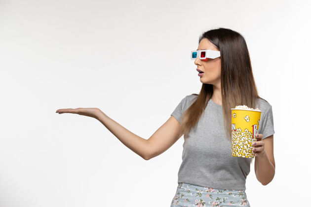 年轻的女性正面图年轻女性手持爆米花 戴着d墨镜在白色表面看电影看孤独电影院
