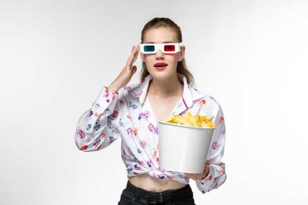 享受正面图：白色表面上戴着d型太阳镜的年轻女性拿着土豆片的篮子太阳镜电影前面