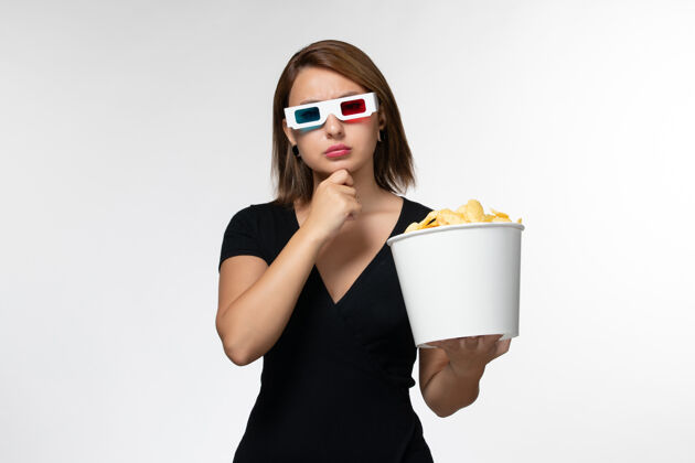 孤独正面图白色表面上戴着d型太阳镜拿着薯片的年轻女性电影举行年轻的女性