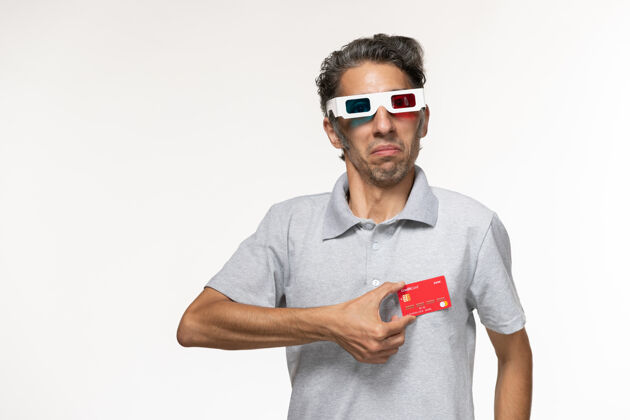 银行正面图年轻男子手持红色银行卡戴着d墨镜在白色表面电影前面年轻的男