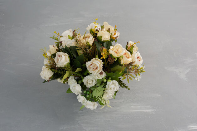 叶子美丽的白玫瑰花束放在灰色的桌子上开花玫瑰自然