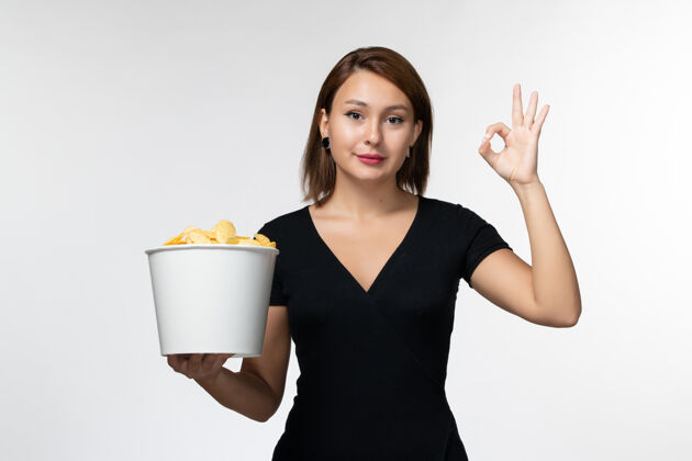 土豆正面图：年轻的女性拿着土豆片篮子 微笑着站在白色的表面上举行美丽篮子