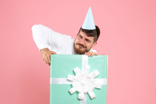 展台正面图：年轻男性站在礼物盒内 粉色情感圣诞照片 人类睡衣派对年轻男性里面礼物