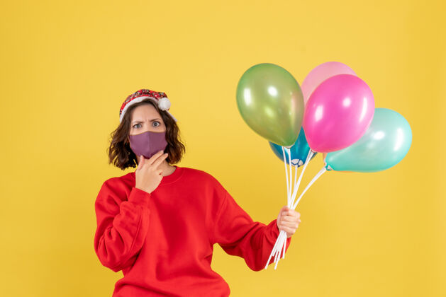 外科口罩正面图年轻女子拿着气球 戴着黄色的无菌面具气球空气颜色