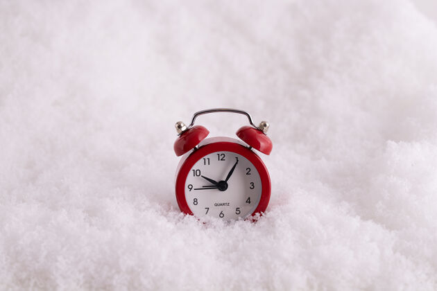 雪雪地里红色闹钟的特写镜头 一个计时到新年的钟闹钟计时器经典