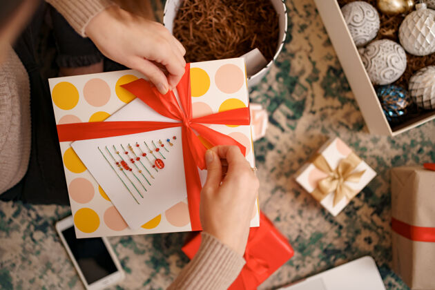 女人近距离的女性手绑在一个工艺礼品盒红丝带蝴蝶结圣诞节前夕包装