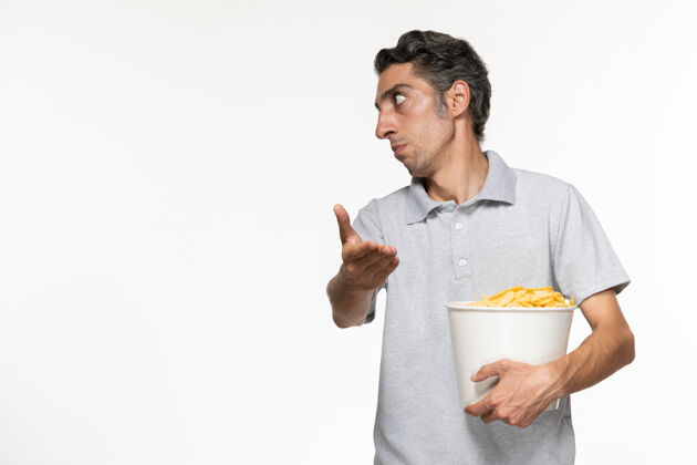电影院正面图：年轻的男性拿着一个装薯片的篮子 和一个坐在白色桌子上的人说话电影土豆某人