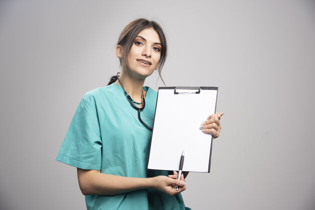 工作女医生拿着剪贴板看着相机健康妇女医院