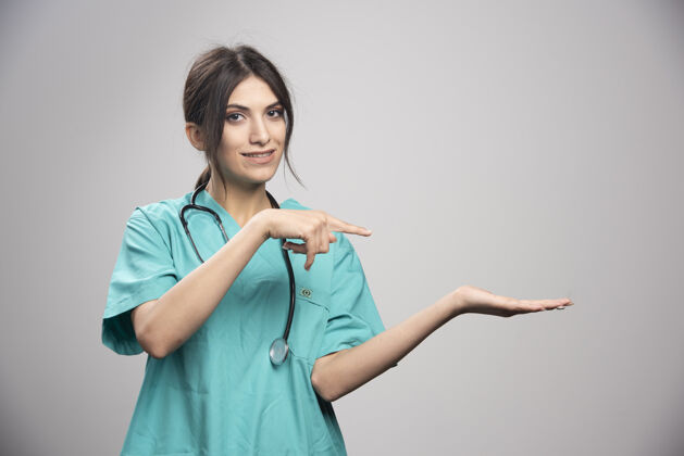 职业穿制服的女医生在灰色的床上摆姿势健康疾病制服