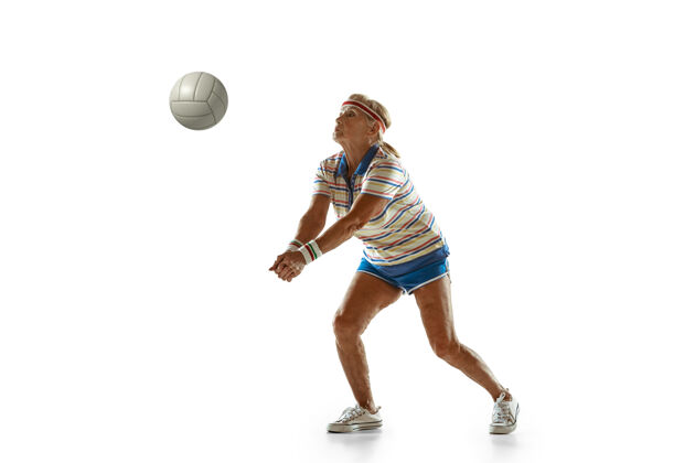 活跃穿运动服的老太太在白墙上打排球人球拍运动