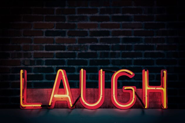 娱乐黑色砖墙背景上写着“笑”的红色霓虹灯标志幽默灯光平板