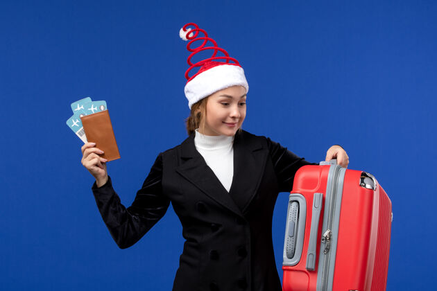 工人正面图：年轻女性拿着票和包在蓝色办公桌上的女人度假度假女人票公司