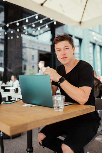 在线坐在桌边用笔记本电脑工作的男人的画像桌子使用成人