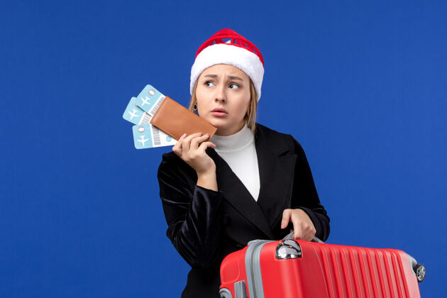 职业正面图年轻女性手持包和机票在蓝色办公桌上度假职业年轻女性景观
