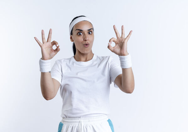 腕带年轻惊讶的白人运动女性戴着头带和腕带做手势确定手标志隔离在白色空间与复制空间手头带空间