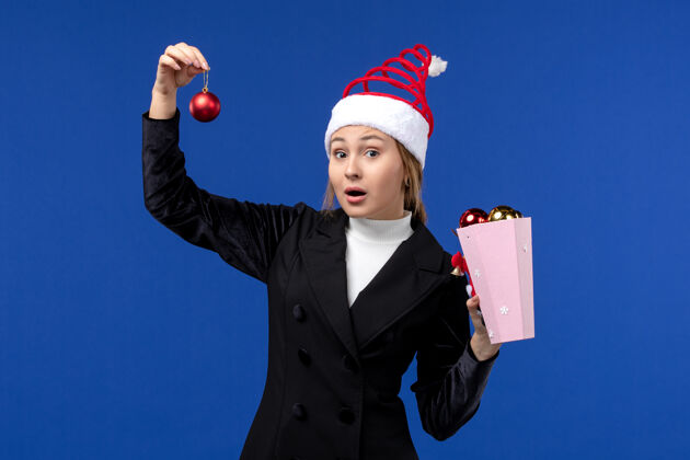 成功前视图年轻女士拿着树玩具在蓝色的墙上蓝色的情绪新年假期西装人人