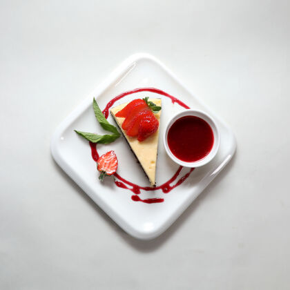 背景一块芝士蛋糕的顶视图和一个草莓放在一个白色背景上的盘子里美食糕点糖