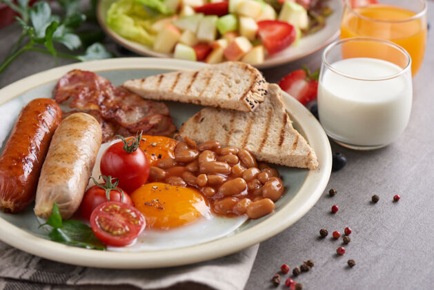 丰盛传统的全英式早餐 盘子里有煎蛋 香肠 西红柿 豆子 吐司和培根欧式杯子烤