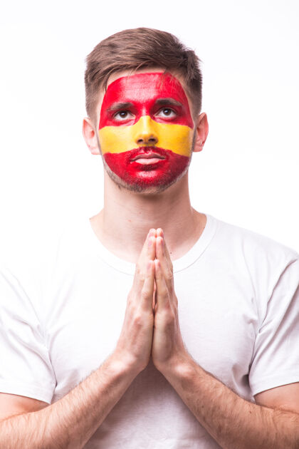 欢乐年轻的西班牙男足球迷用祈祷的手势孤立在白墙上年轻油漆球迷