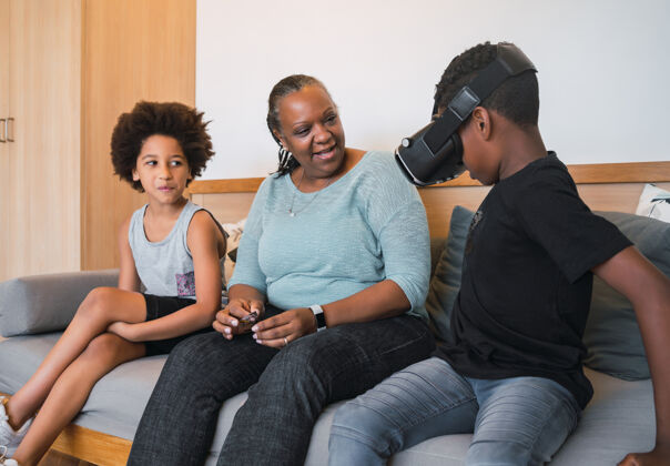 老人非裔美国人的祖母和孙子孙女在家里玩vr眼镜的画像家庭和技术概念在一起设备游戏
