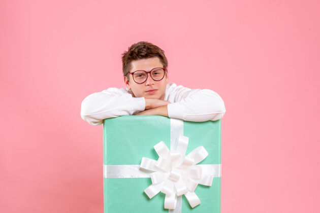 圣诞正面图：穿着白色衬衫的年轻男性 粉色背景上有礼物情感睡衣风景