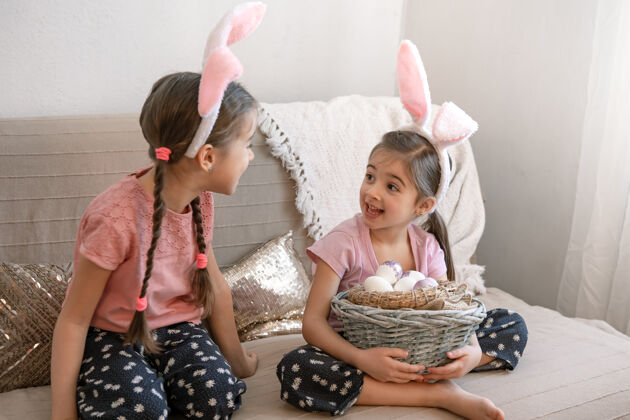 准备有兔子耳朵的小姐妹们 家里的沙发上放着复活节彩蛋复活节摆姿势鸡蛋