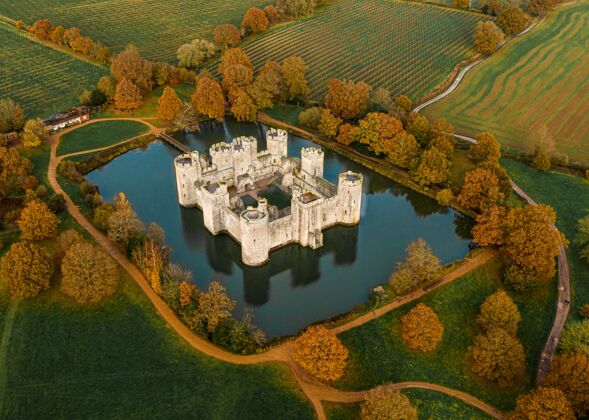 中世纪空中拍摄的一个宏伟的古堡在一个湖的周围树木和农场包围云古老历史